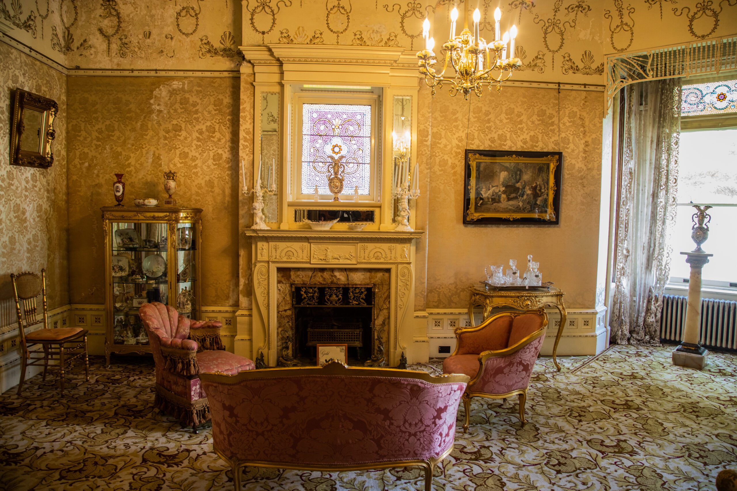 interior of the 1890 House parlor room, with champagne colored wall paper, fireplace and pink furniture.