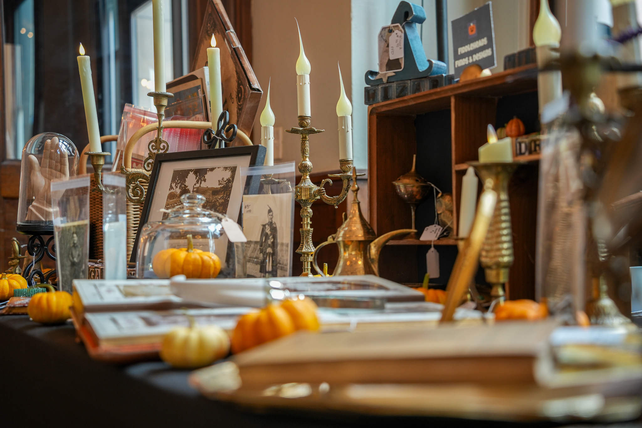 Table spread of antiques, brass candle sticks, old photos and tiny pumpkins at the Cortland Curiosities Market