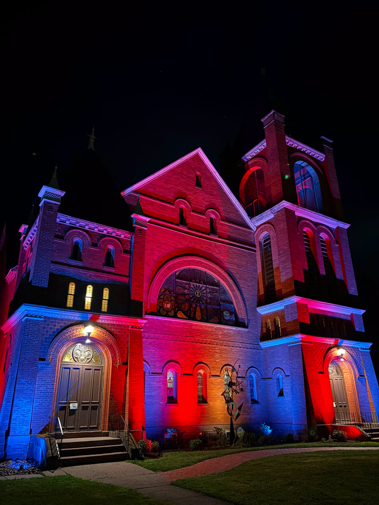 Historic church at night, illumined by blue, red and purple up lighting.